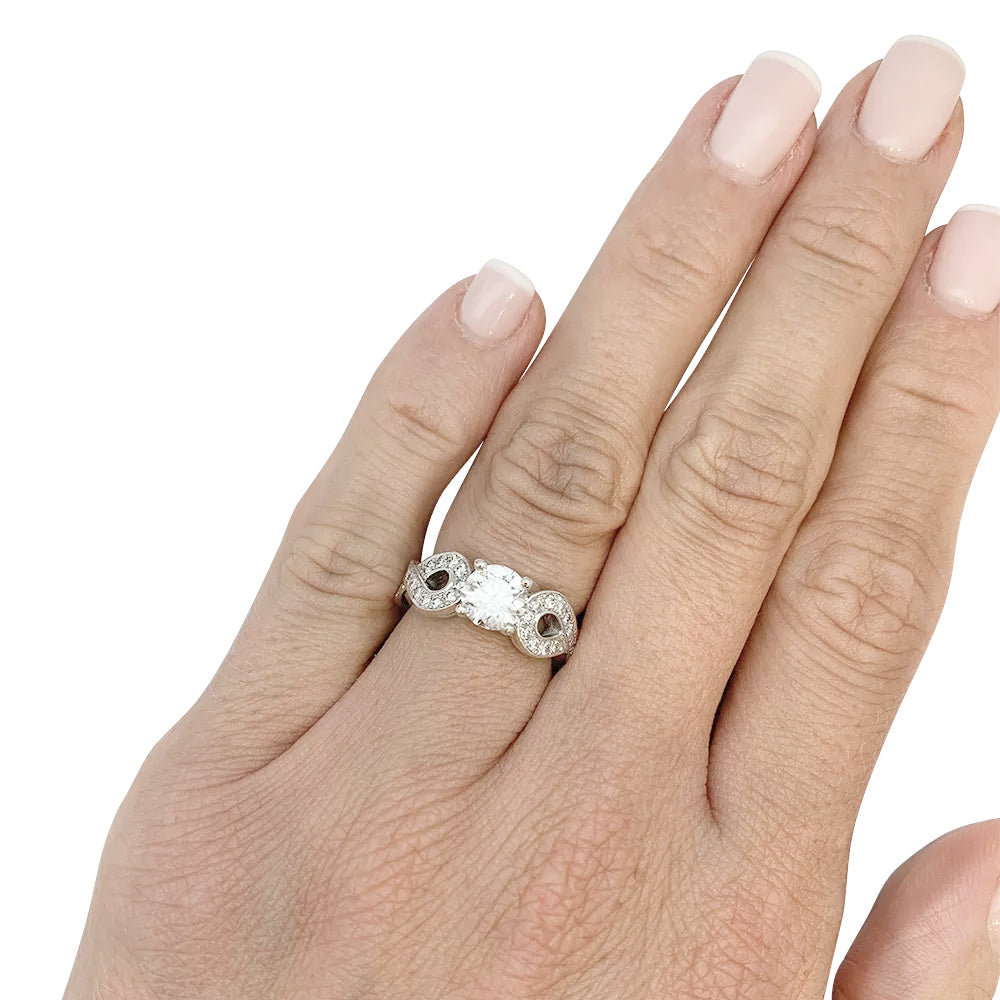 Solitaire en or blanc 750/000 centré d’un diamant taille brillant de 0,94 carat qualité E/VS1,certificat GIA N°6147299507 (2012) épaulé de noeuds sertis de diamants. Poids brut: 8,6 Grammes. 8