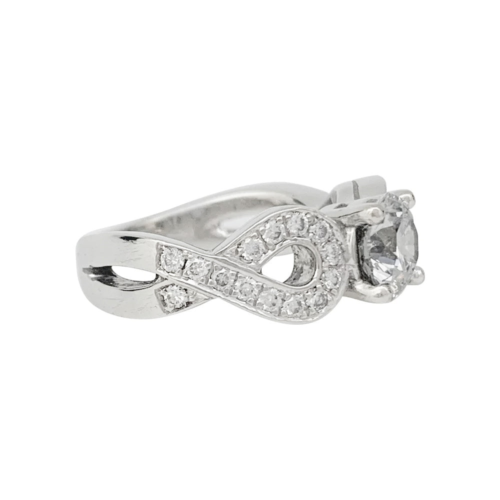 Solitaire en or blanc 750/000 centré d’un diamant taille brillant de 0,94 carat qualité E/VS1,certificat  GIA N°6147299507 (2012) épaulé de noeuds sertis de diamants.  Poids brut: 8,6 Grammes. 2