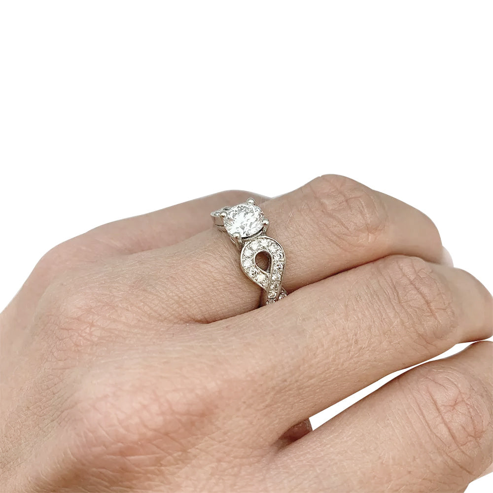 Solitaire en or blanc 750/000 centré d’un diamant taille brillant de 0,94 carat qualité E/VS1,certificat  GIA N°6147299507 (2012) épaulé de noeuds sertis de diamants.  Poids brut: 8,6 Grammes. 7